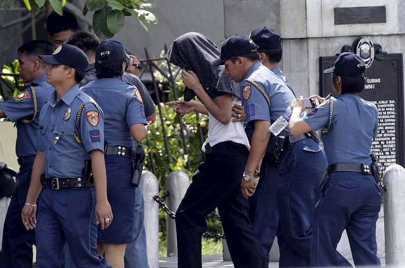 Agentes de la Policía filipina escoltan a uno de los 25 rehenes tras ser liberado.