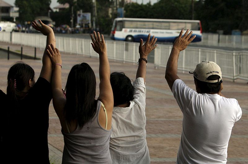 Varias personas animan al secuestrador del autobús a que se rinda.