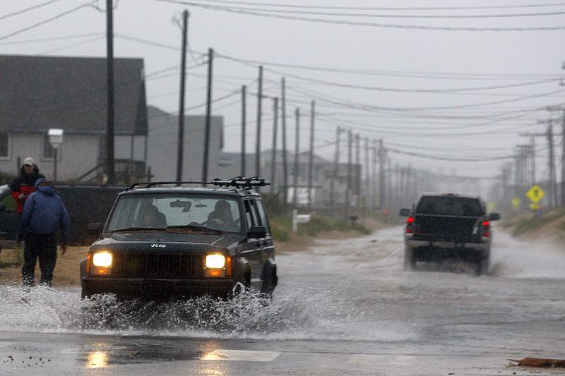 Cars pass along a flooded beach road during Hurricane Earl in Kill Devil Hills, North Carolina
