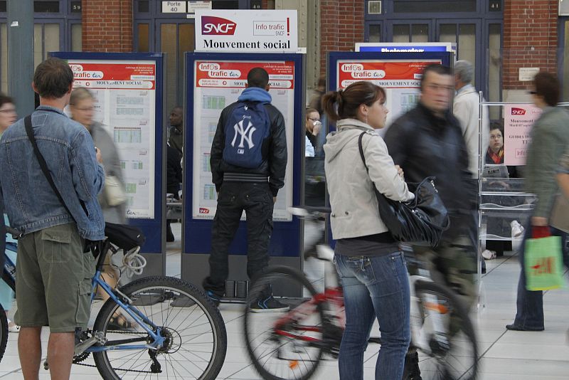 Commuters check a train schedule at the Lille-Flandres station during a nationwide strike over pension reform