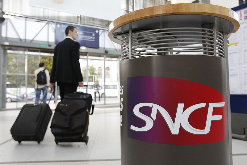 A commuter walks past a SNCF railway logo at Nantes' railway station during a nationwide strike over pension reforms in Nantes