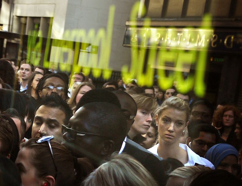 Commuters are reflected in the window of a bus as they queue during a strike by underground transit workers, outside Liverpool Street rail station in London