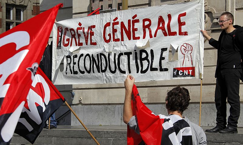 People hold a banner which reads "General strike renewable" as private and public sector workers prepare to demonstrate over pension reforms in Lille