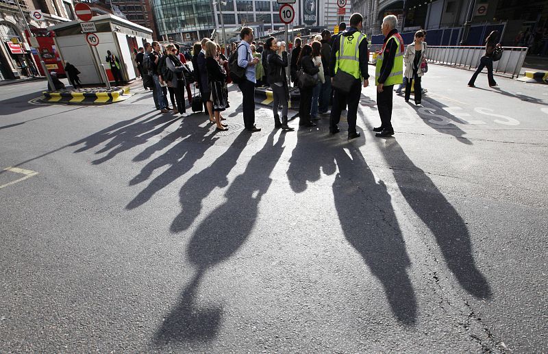 Commuters queue for buses at Victoria station in London