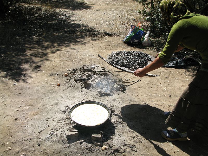La masa para hacer el pan se coloca en un recipiente metálico sobre el fuego y se cubre con más brasas.