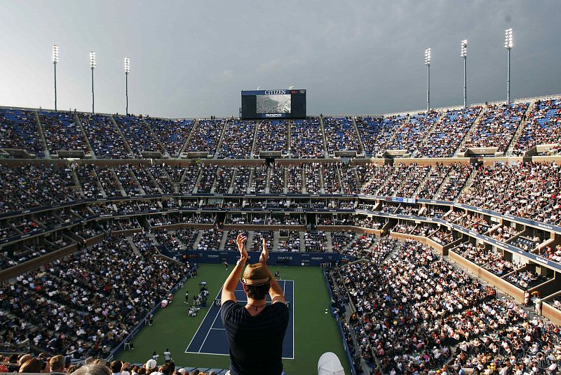 Un aficionado en lo alto de la grade del Arthur Ashe Stadium se levanta para aplaudir durante el partido