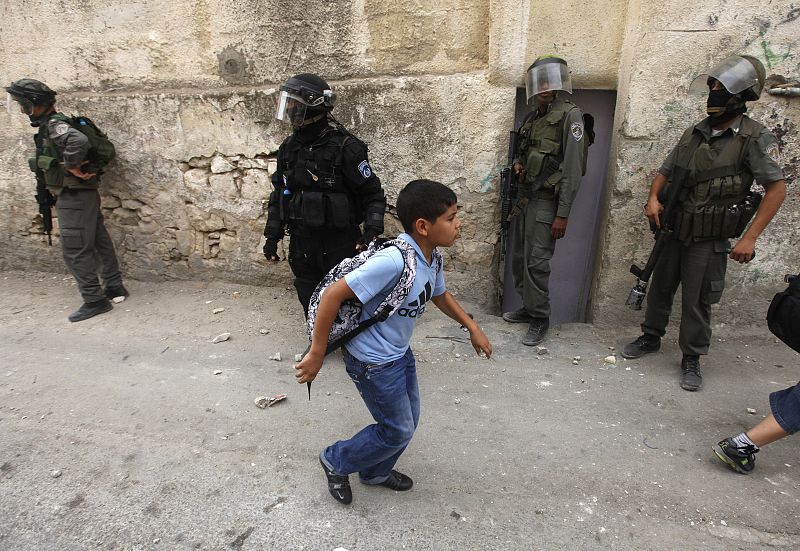 Un niño palestino intenta refugiarse durante los enfretamientos