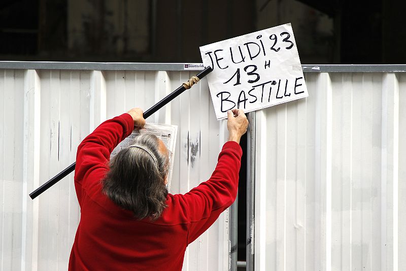 A labour union activist installs a placard which reads "Thursday 23, 13h at Bastille place" on a security panel at the Gare Saint Lazare station in Paris