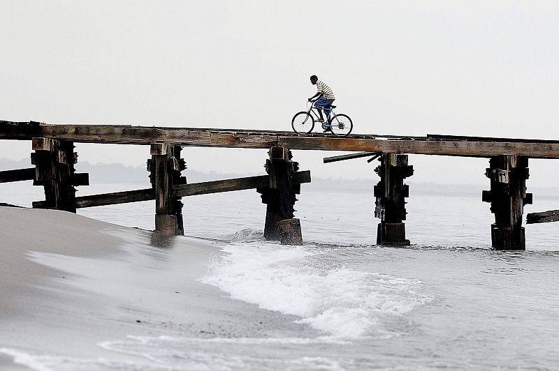 Un ciudadano hondureño transita en bicicleta bajo la lluvia generada por la depresión tropical "Matthew" en la ciudad de La Ceiba, al norte de Honduras