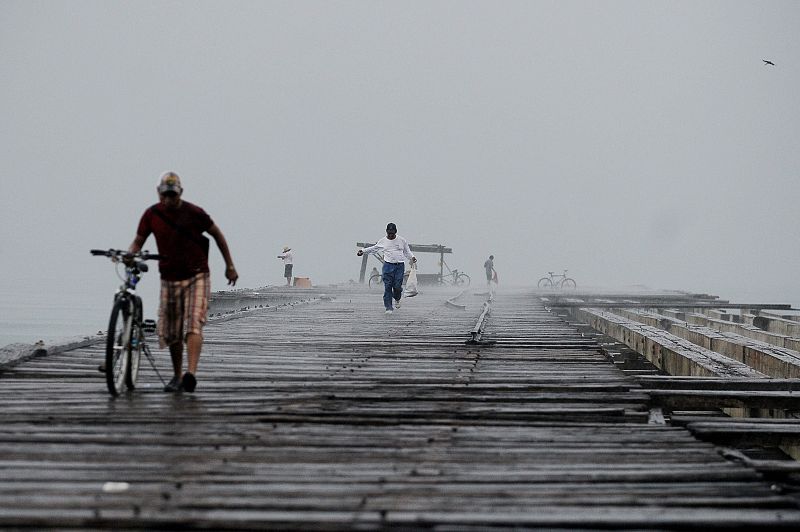 Un ciudadano hondureño camina bajo la lluvia generada por la depresión tropical "Matthew" en un viejo muelle de la ciudad de La Ceiba, al norte de Honduras.