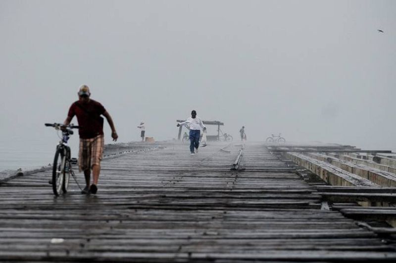 Un ciudadano hondureño camina bajo la lluvia generada por la depresión tropical "Matthew" en un viejo muelle de la ciudad de La Ceiba, al norte de Honduras.