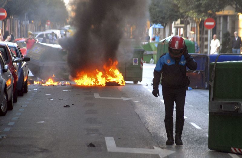 Una barricada arde en una calle adyacente a la estación de autobuses de Gijón.