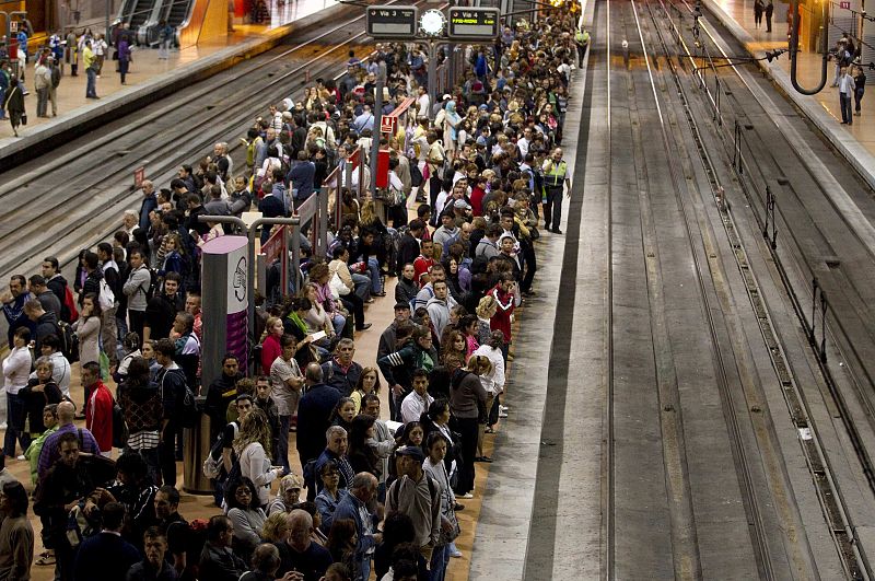 Multitud de pasajeros esperan en los andenes de la estación de Atocha (Madrid).