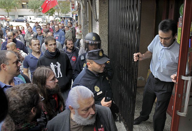 El dueño de un establecimiento echa el cierre ante la insistencia de un piquete informativo, esta mañana en Santiago de Compostela.