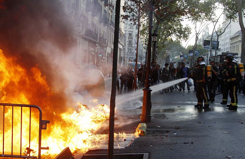 Firefighters put out a burning barricade during a general strike in central Barcelona