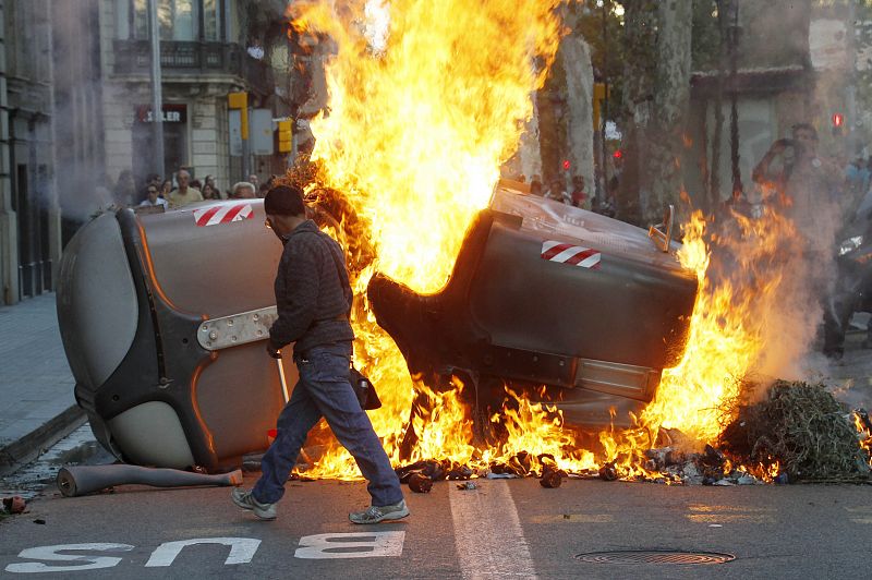 A man walks past a burning barricade during a general strike in central Barcelona