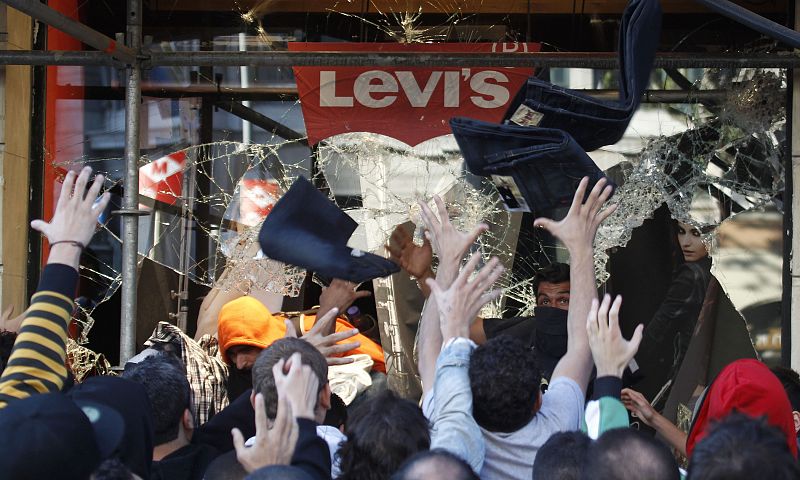 Protesters catch clothing thrown out of a clothing store by their colleagues during a general strike in central Barcelona