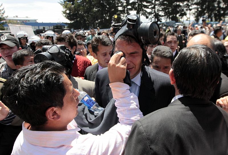 El presidente ecuatoriano, Rafael Correa (c), es protegido del gas lacrimógeno con el que le han atacado los protestantes