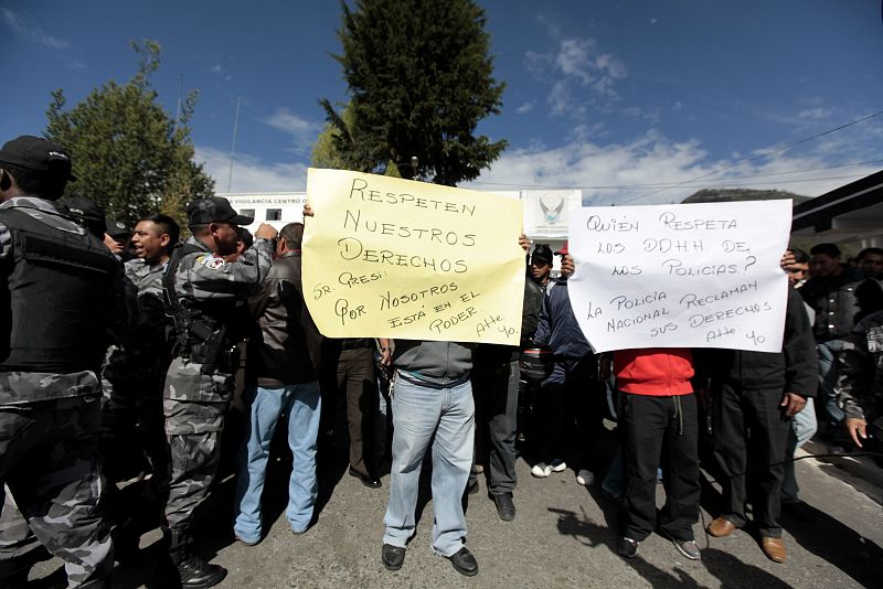 Un policía sostiene un cartel en el que pide a Correa que respete sus derechos y le recuerdan que "está en el poder" por ellos