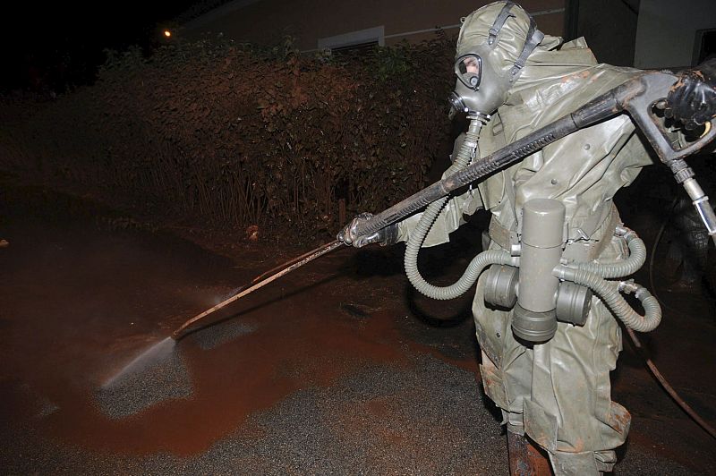 Un soldado húngaro con un traje protector limpia la zona cubierta por el lodo tóxico