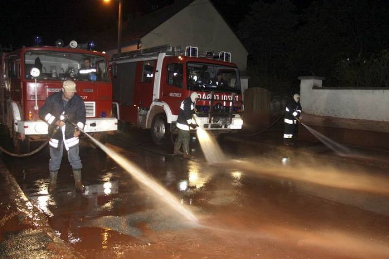 Varios bomberos limpian una calle cubierta con el lodo tóxico que se ha derramado