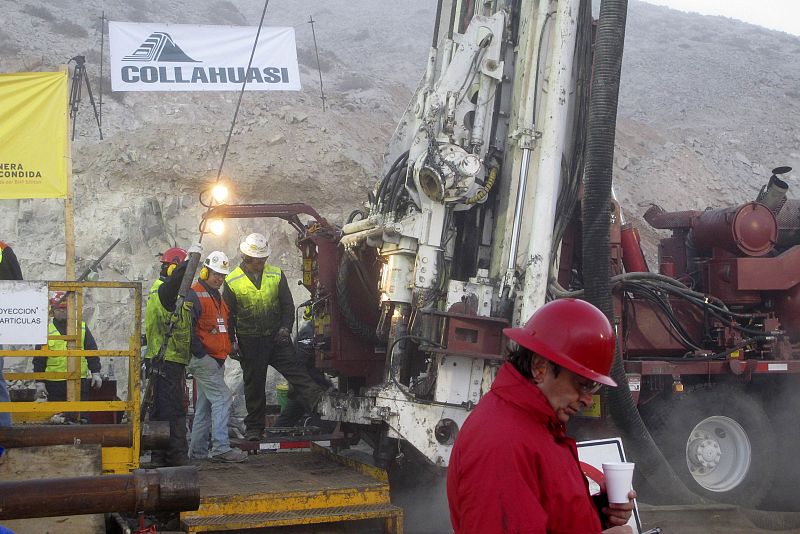 Chile's Mining Minister Golborne drinks coffee as workers operate the T 130 drilling machine before completing an escape hole for the trapped miners at San Jose mine