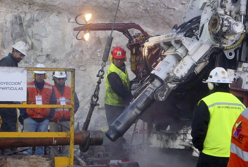 Workers operate the T 130 drilling machine as they prepare the last tube to complete an escape hole for the miners trapped deep underground at San Jose mine