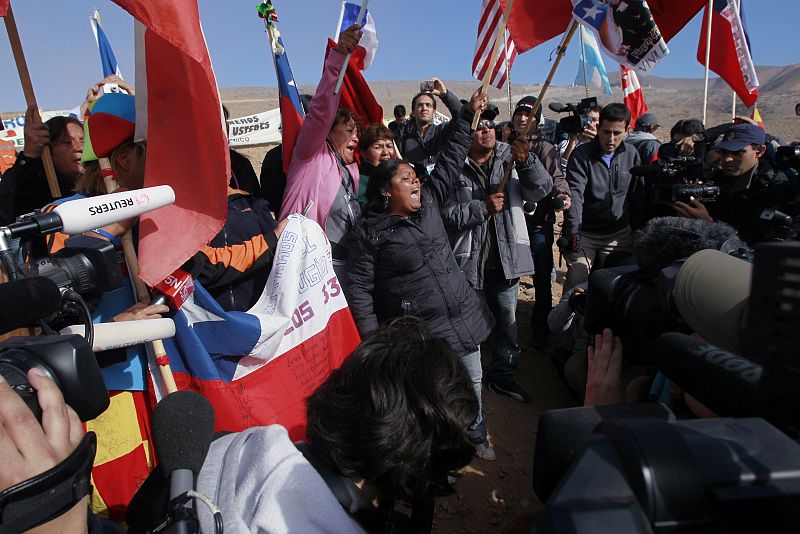 Relatives shout slogans after the T 130 drilling machine completed an escape hole for the miners at San Jose mine