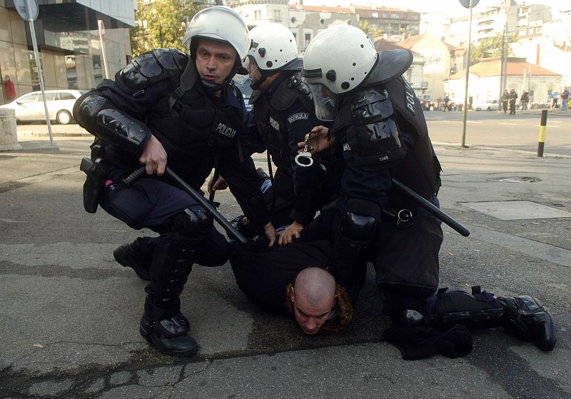 A protester is detained by riot police during riots in Belgrade