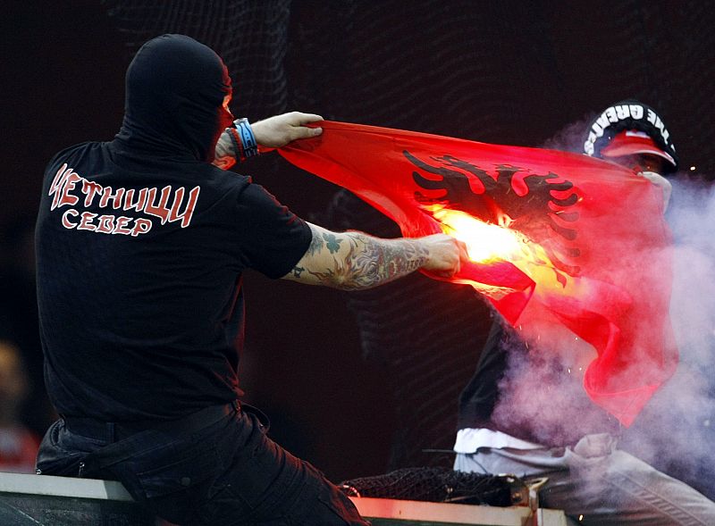 Un ultra serbio quema una bandera de Albania.