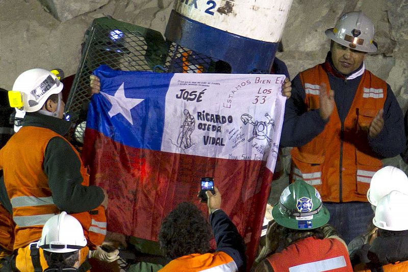 El minero José Ojeda, de 46 años, despliega una bandera chilena mientras sale de la cápsula tras ser rescatado en séptimo lugar de la mina San José.