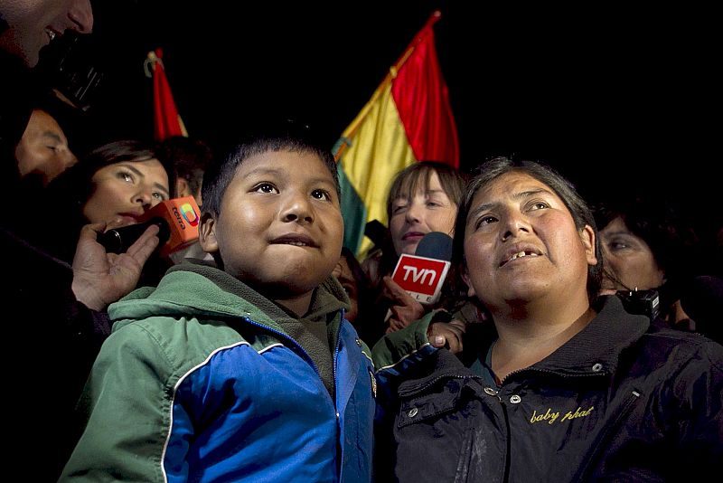 Marcelo Pacaje, (iz), sobrino del minero boliviano Carlos Mamani, observa por televisión el rescate de su tio en el yacimiento San José, en Copiapó.