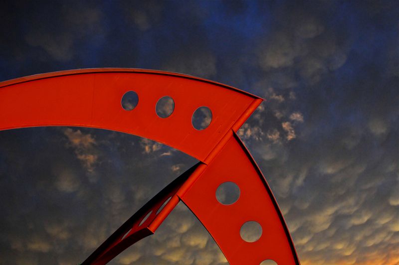 Simetría rota. La imagen muestra una escultura que hay en la entrada principal del Fermilab. El arco está situado justo encima de la carretera de entrada y si se mira desde abajo parece perfectamente simétrico. La simetría se rompe desde cualquier