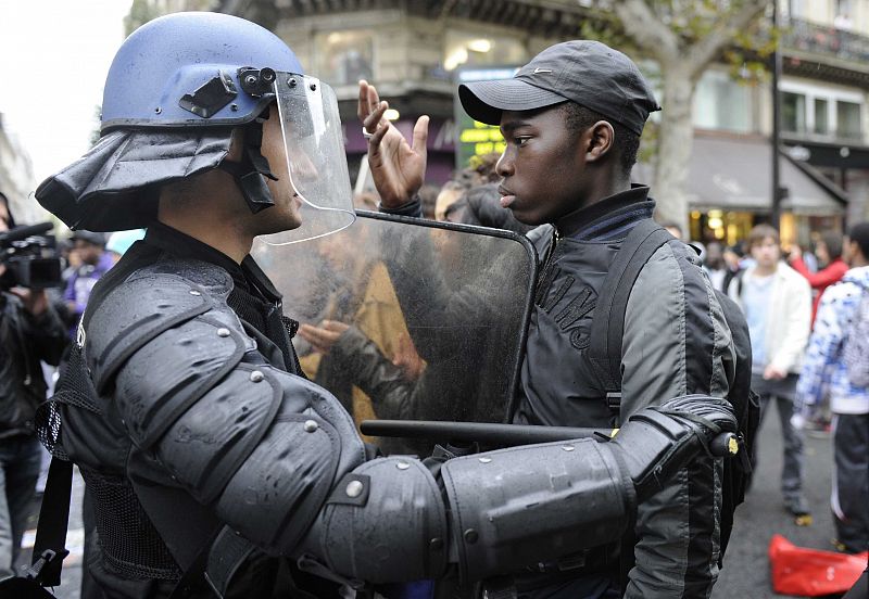 A French high school student faces anti-riot gendarmes during a student demonstration at the Place de la Republique in Paris