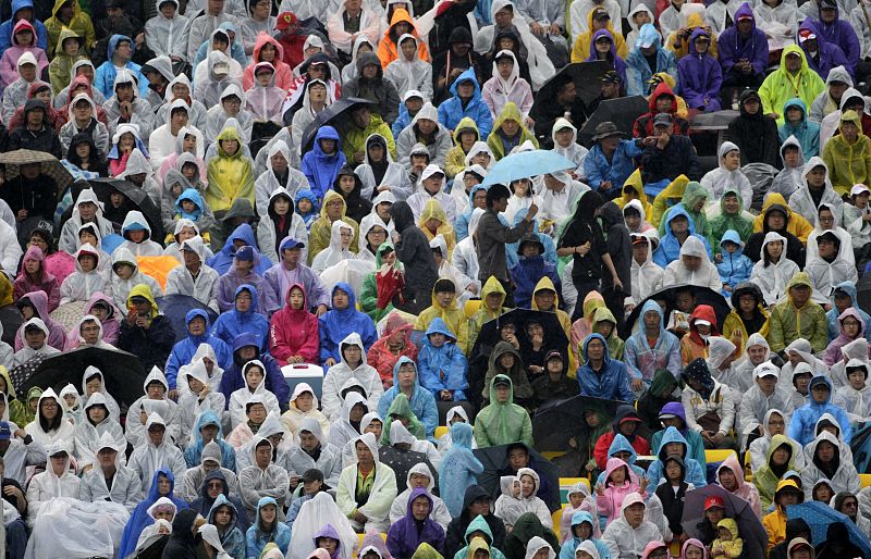 Spectators wearing raincoats sit in the stands as it rains during the South Korean F1 Grand Prix at the Korea International Circuit in Yeongam