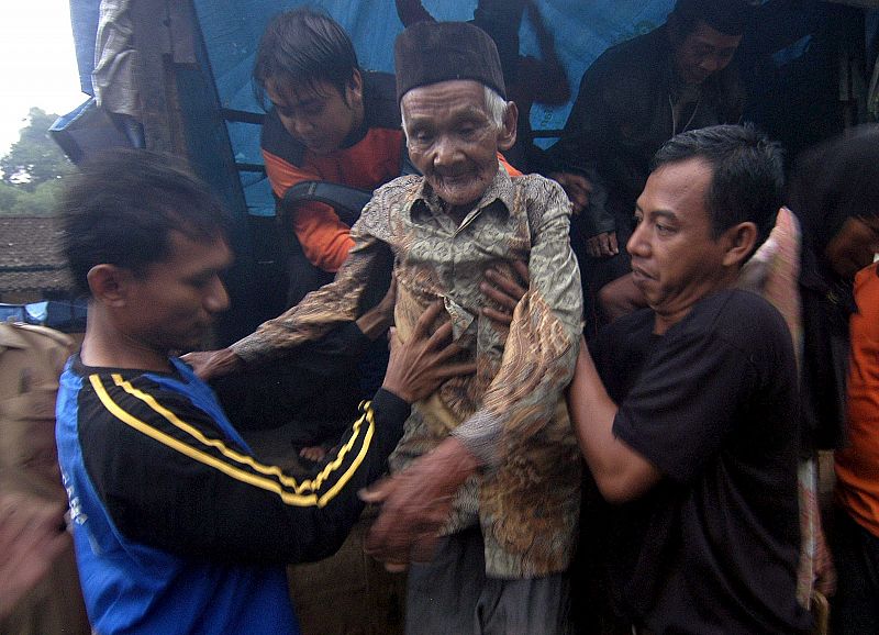 Un par de hombres ayudan a un anciano a bajar de un vehículo durante las labores de evacuación de la población en la localidad de Bawukan, en Java Central.