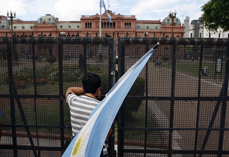 Un joven sostiene una bandera de Argentina mientras mira la Casa Rosada en Buenos Aires (Argentina)