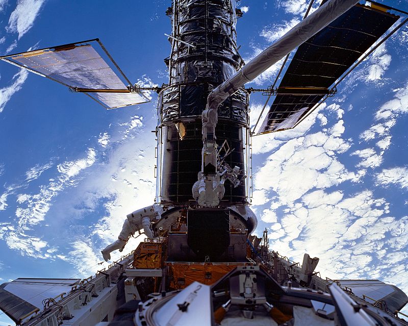 Michael Foale y Claude Nicollier trabajando en el mantenimiento del Hubble, atracado en la bahía de carga del Discovery, durante la misión STS-103