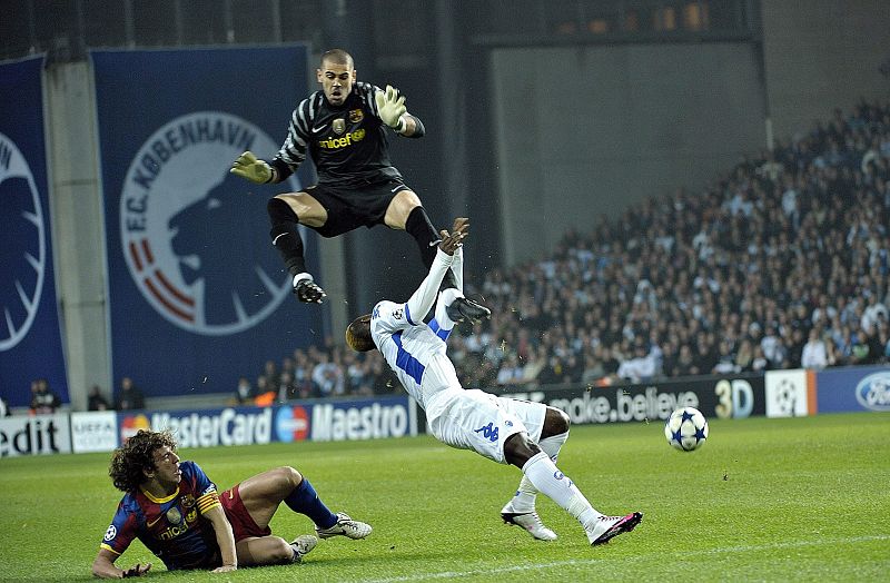 El jugador Dame N' Doye del Copenhagen choca contra el arquero del Barcelona Victor Valdes.