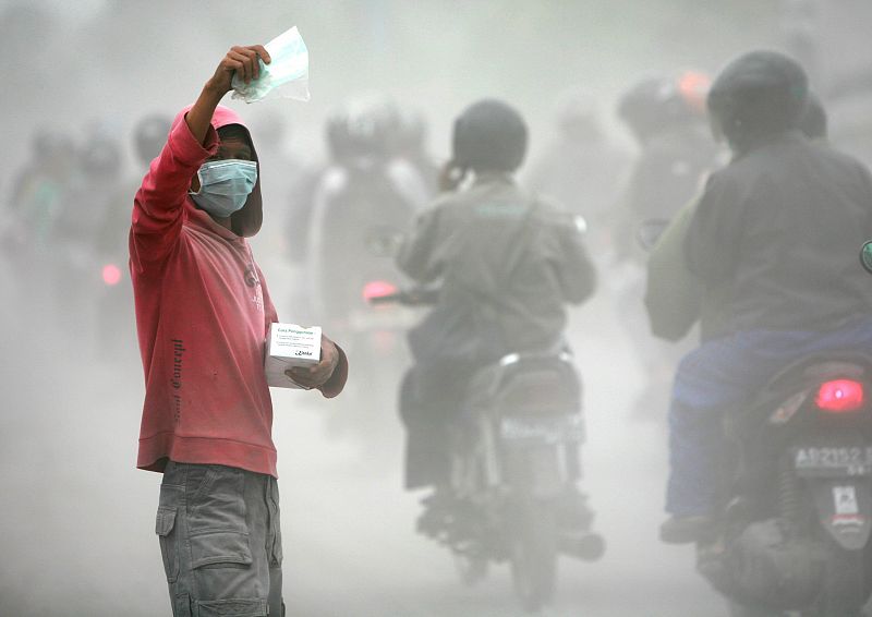 Un vendedor ofrece máscaras protectoras de la ceniza que ha dificultado notablemente la respiración.