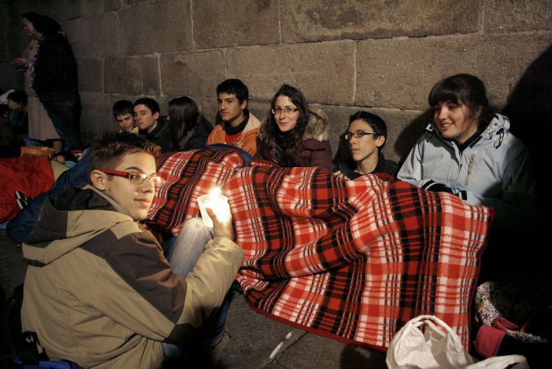 Un grupo de jóvenes aguantan el frío como pueden mientras esperan para acceder a la plaza del Obradoiro.