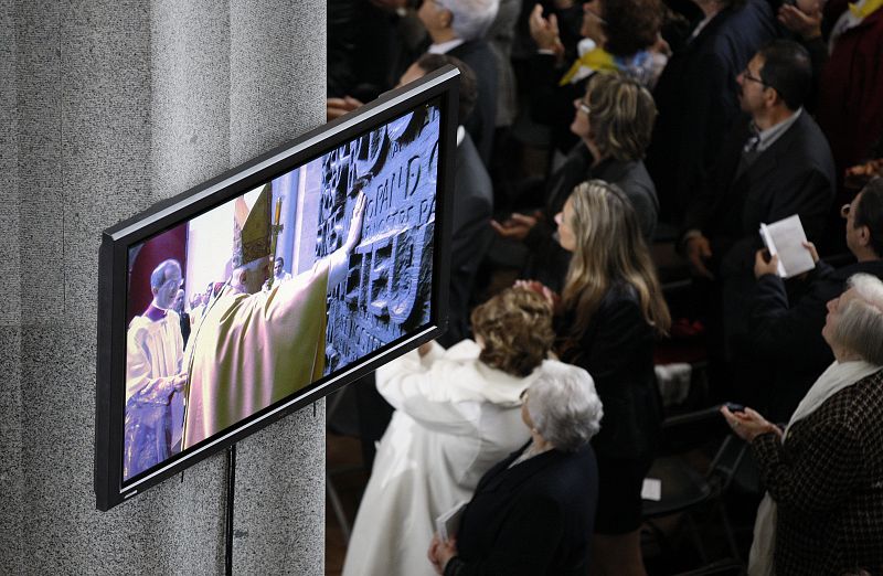 Númerosas personas siguen atentamente la llegada del papa Benedicto XVI por la puerta de la Gloria momentos antes de la celebración de la misa.