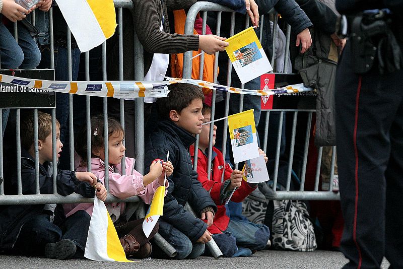 Un grupo de niños con banderas vaticanas esperan el paso de la comitiva.