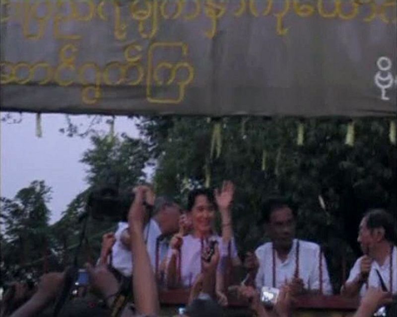 A still image taken from video shows Aung San Suu Kyi greeting supporters outside her home in Yangon