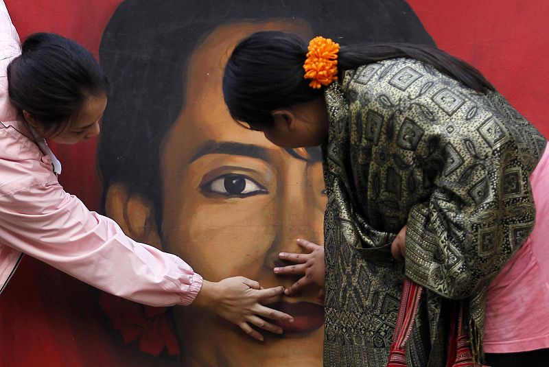 Supporters of Myanmar's pro-democracy leader Suu Kyi clean her portrait during celebrations in New Delhi