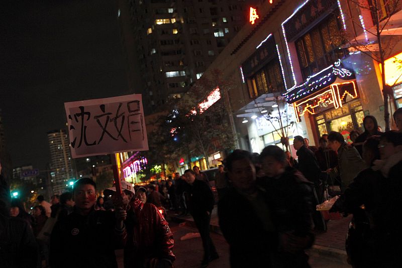 Dos hombres sujetan un cartel con el nombre de una persona desaparecida cerca del edificio arrasado por el fuego