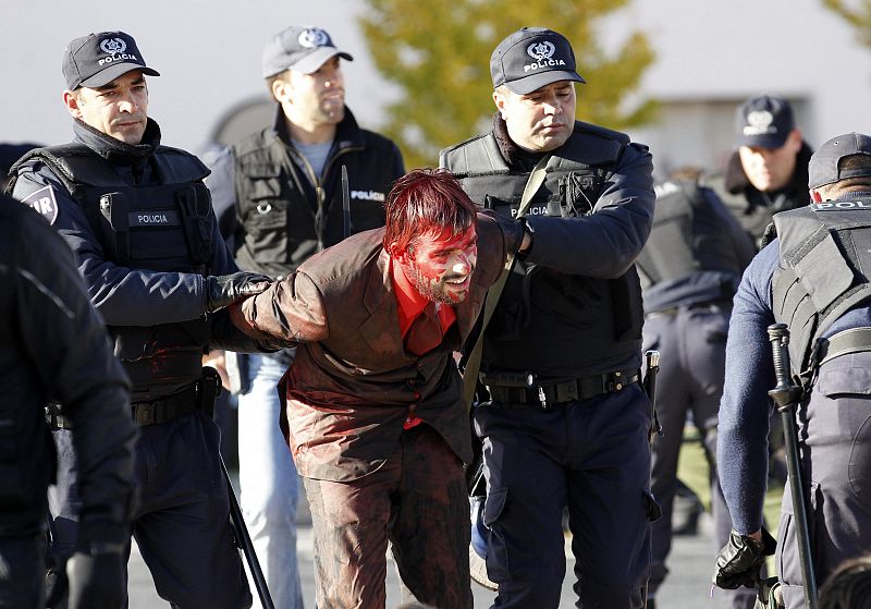 A man is escorted by police during a protest against the NATO summit in Lisbon