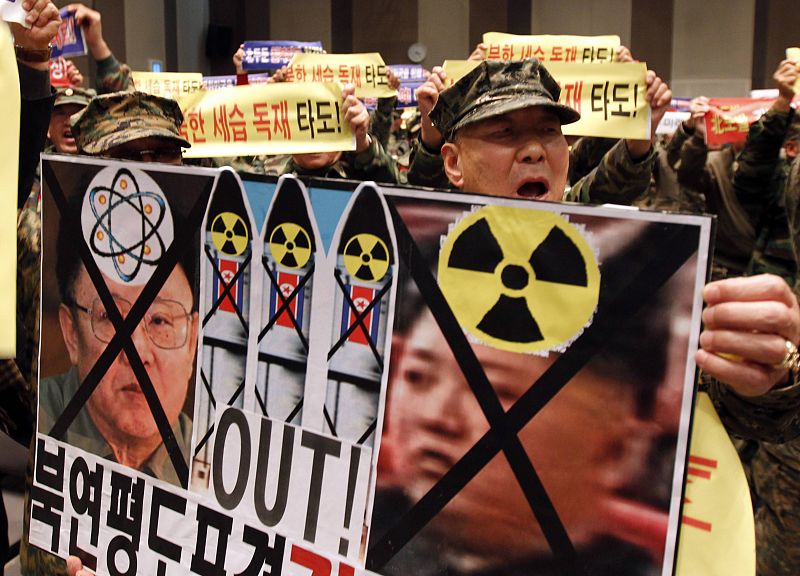 Un grupo de veteranos de guerra gritan consignas con el retrato del difamado líder norcoreano Kim Jong-il en un mitin de denuncia.