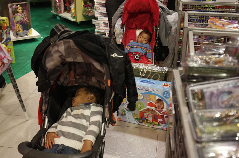 Children sleep in their strollers at Toys R Us on Black Friday in New York