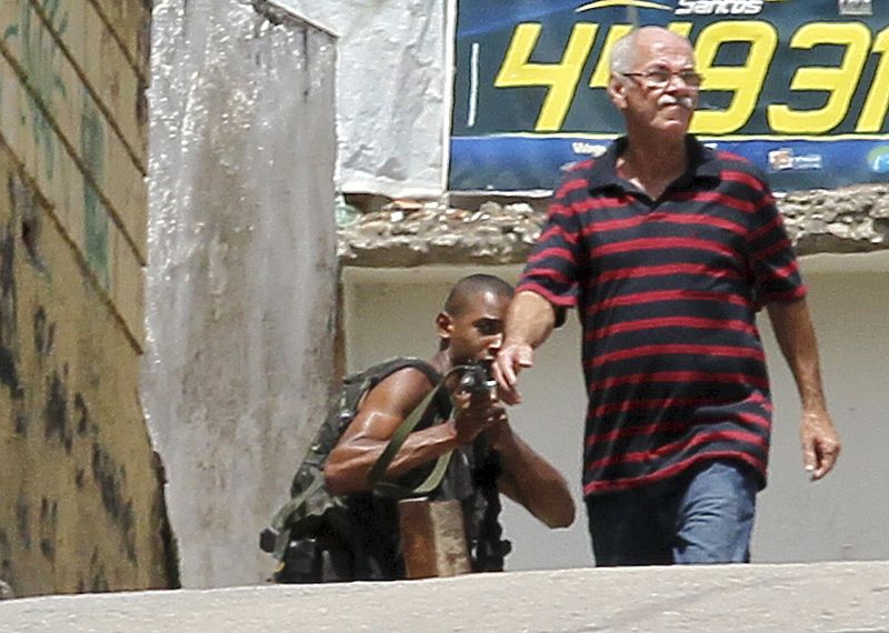 Un criminal junto a un vecino de la favela de Grota encañona a las fuerzas de seguridad.